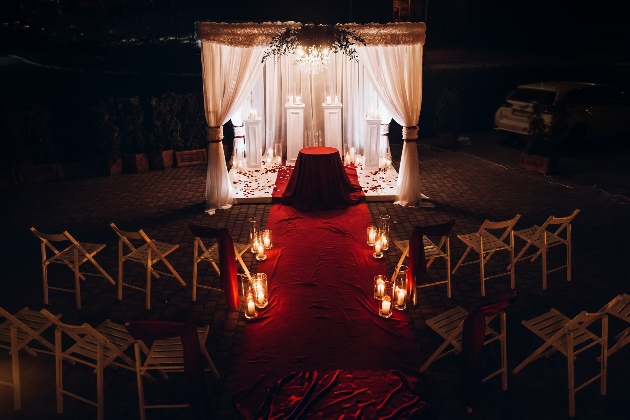 red aisle leading to podiums for the wedding, at night lots of candles
