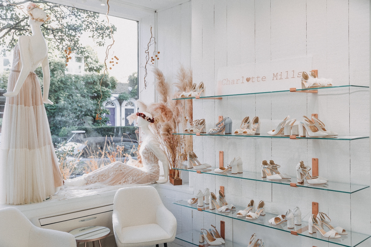inside shop store with rows of shoes on the wall and wedding dresses on mannequins in the window