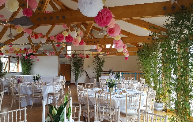 reception room with white walls and beamed ceiling with pompom garlands hanging from the ceiling