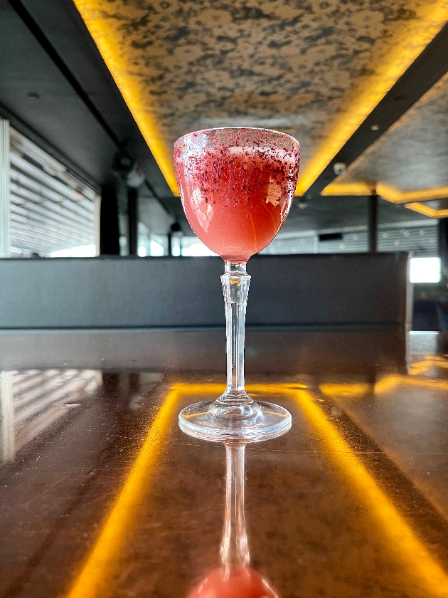 red cocktail in a glass on a bar