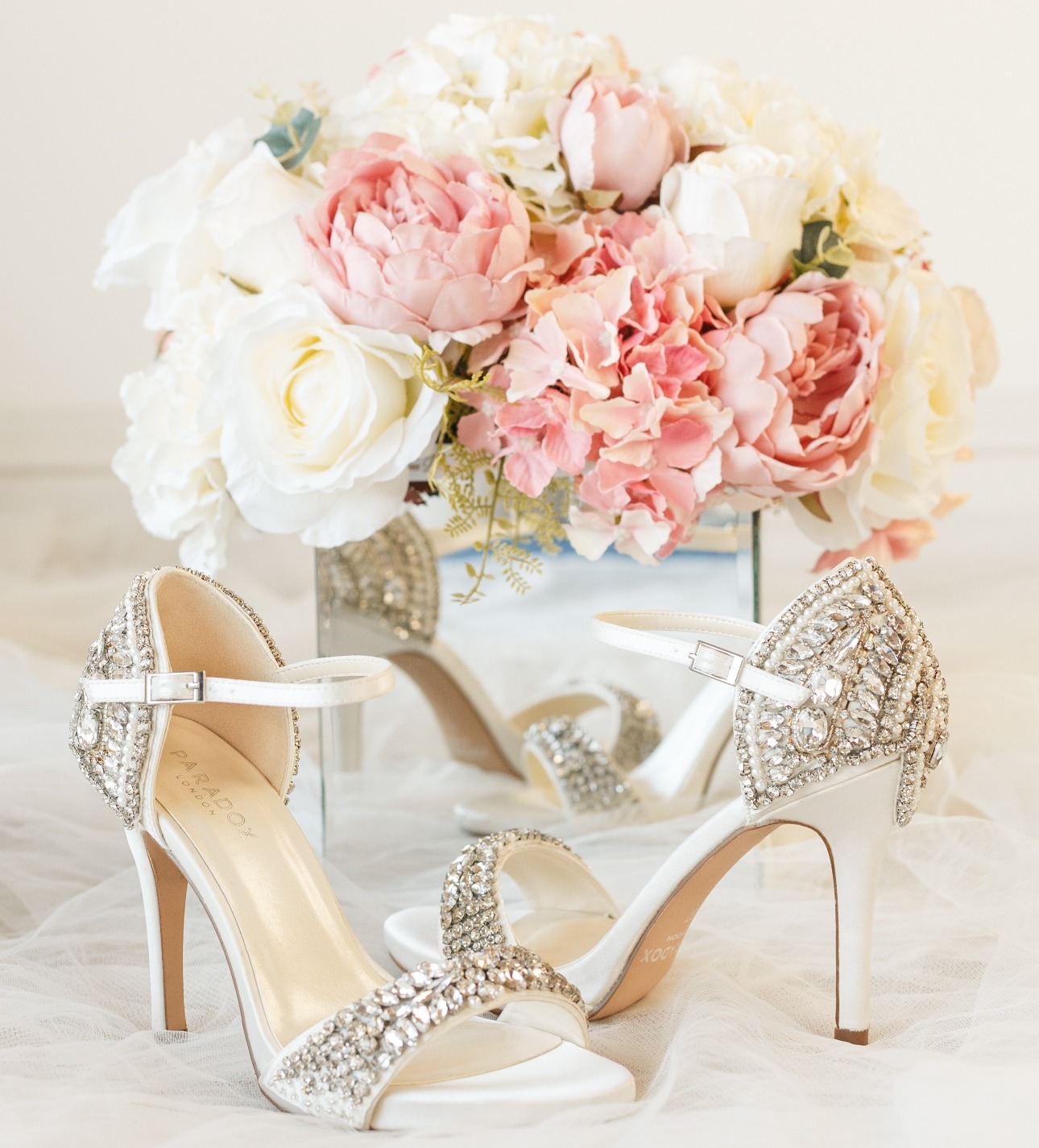 pair of diamond encrusted shoes in front of a floral bouquet 