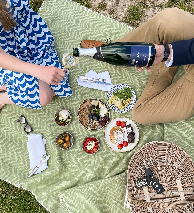two people having a picnic on a blanket with food and champagne