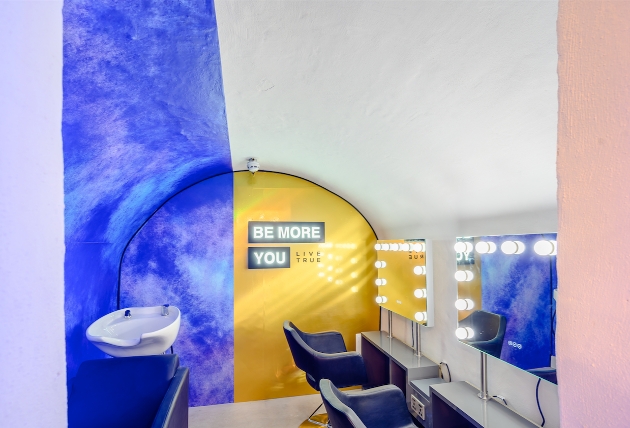 area of salon enclosed with bright coloured walls and two chair with hollywood light mirrors