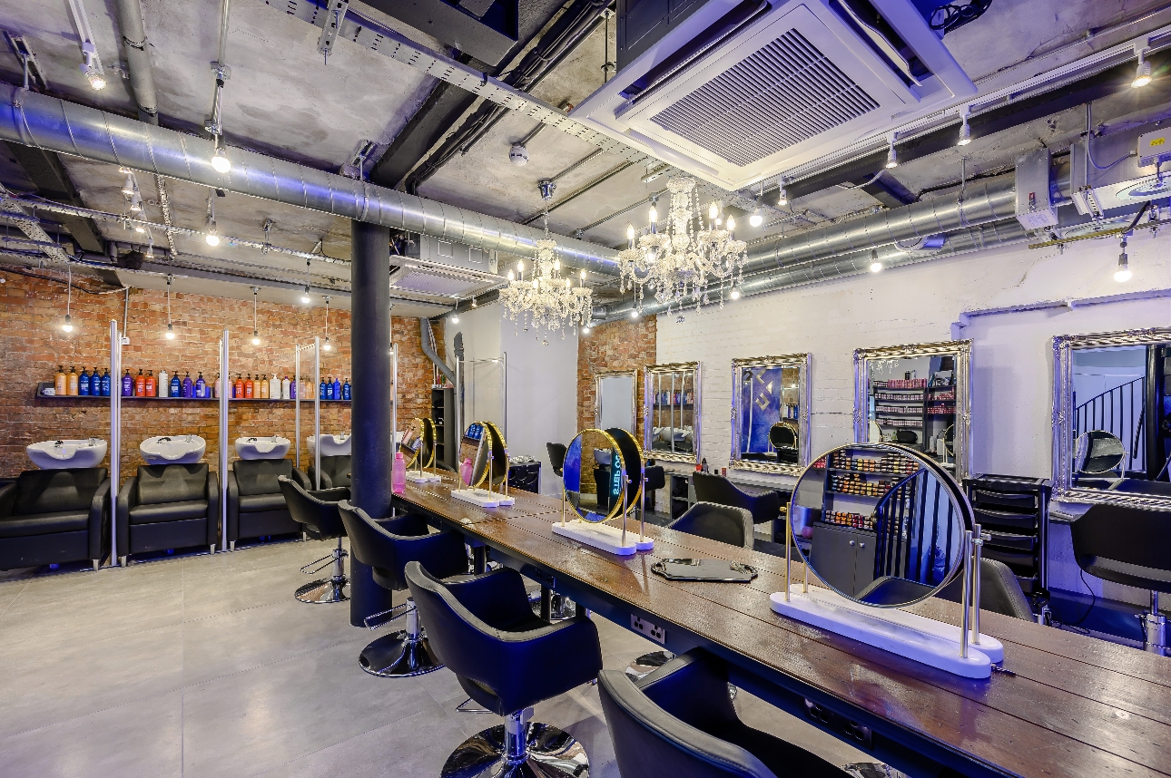inside of salon, industrial chic, exposed pipes and vents, wooden tables and brick walls