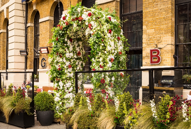 brick hotel front with large victorian industrial windows and huge flower arch at entrance