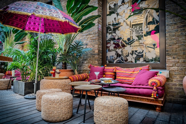 wooden decking with sofas and wicker tables outside and indian material parasols