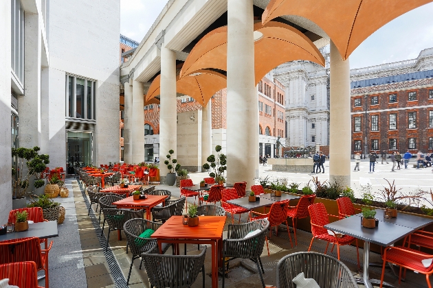 terrace with large white columns and orange canopies over dinning tables and chairs