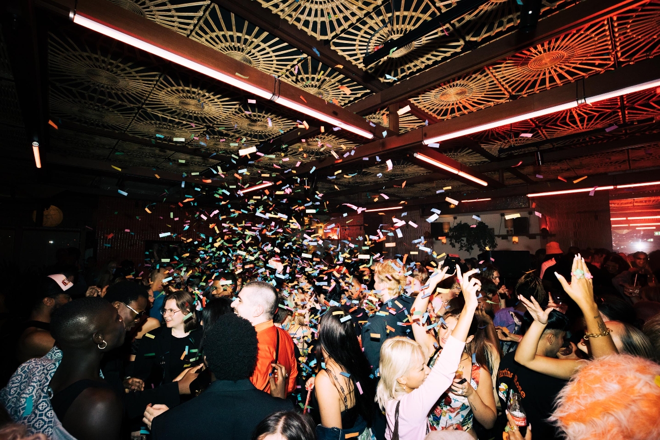 people in a club dancing with rainbow confetti coming from ceiling