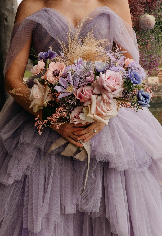 bride in large purple ballgown carrying large bouquet