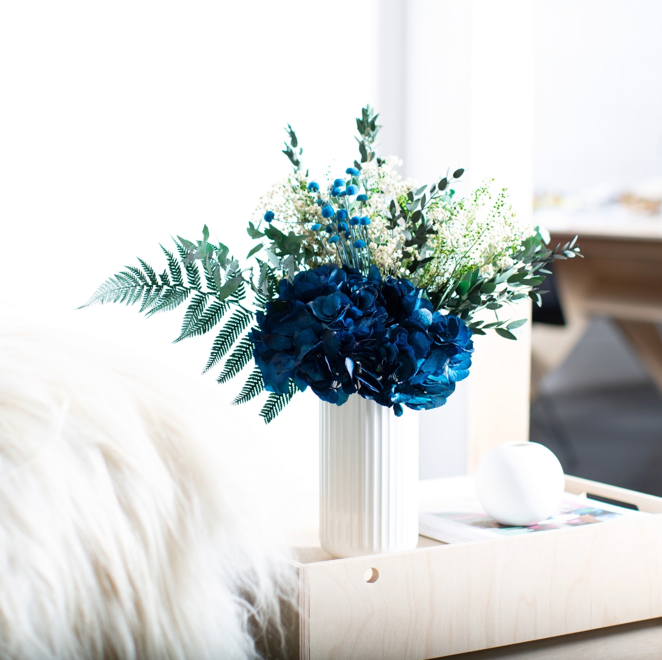dark blue and green dried flowers displayed in a white vase