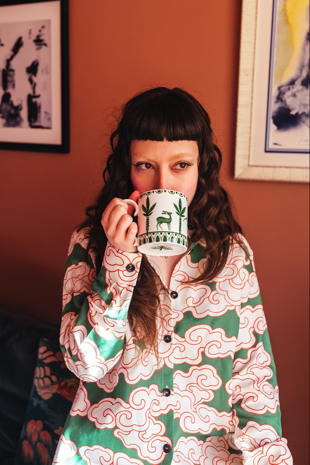 person in green and pink pjs drinking a from a mug