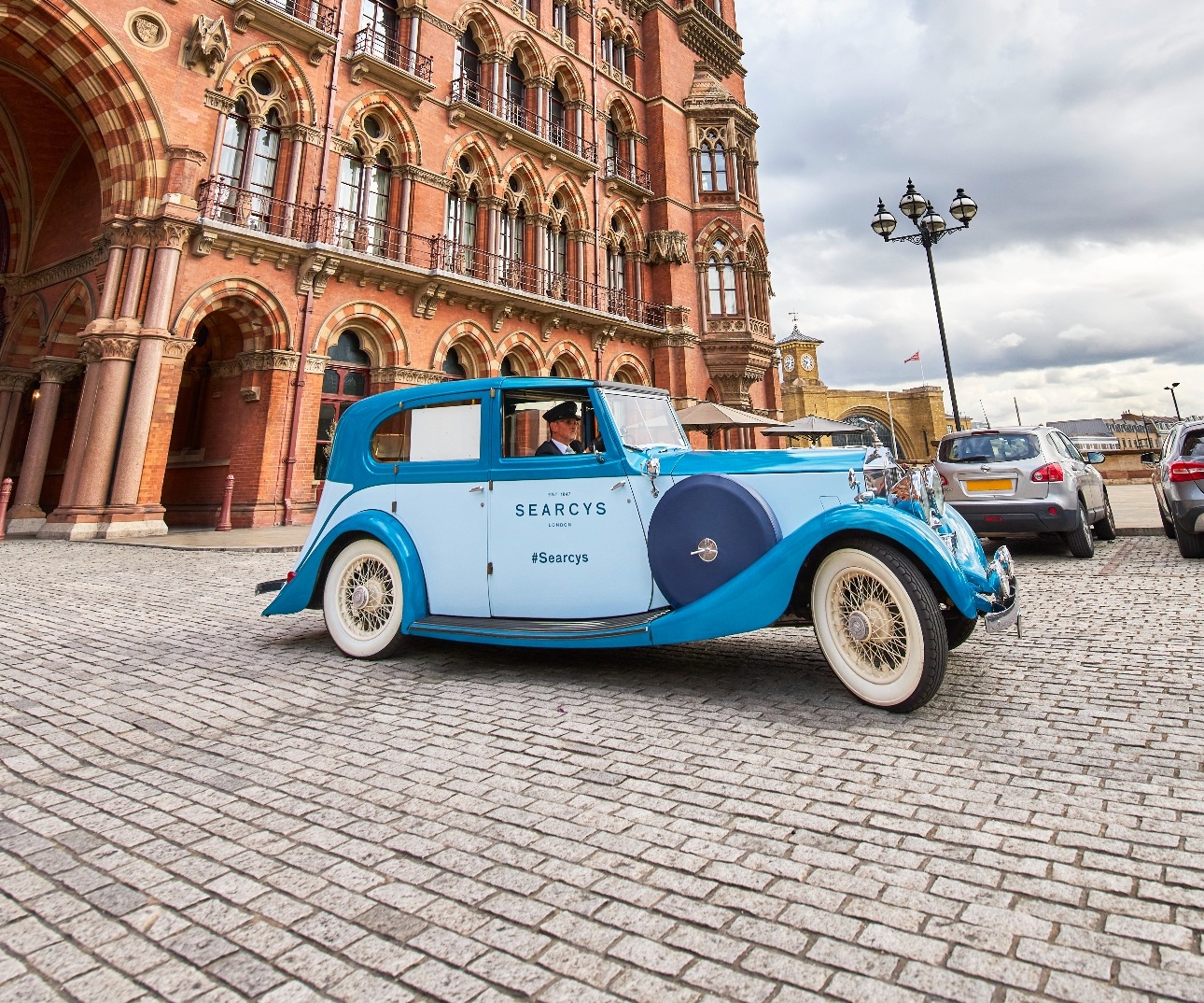 blue rolls royce driven by a chauffeur at london landmark