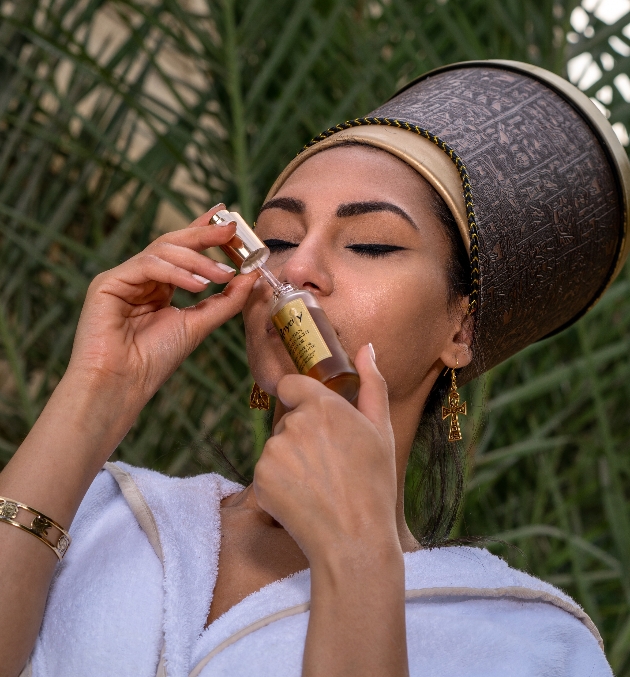 Women dressed in ancient Egyptian attire smelling contents of Hayarty beauty bottle