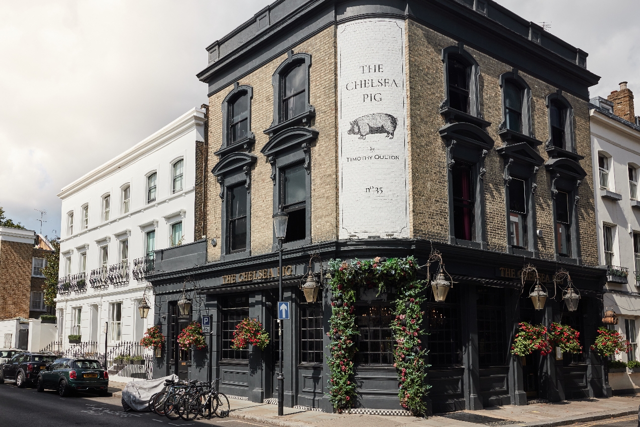 corner pale brick and black facade pub on london street floral arch around the door