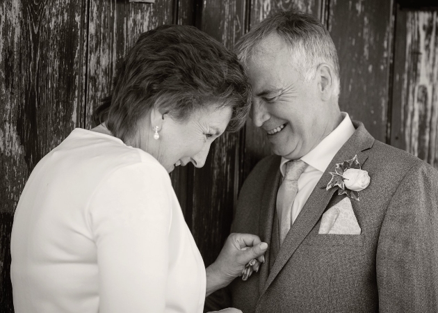 older bride and groom laughing together in black and white photo