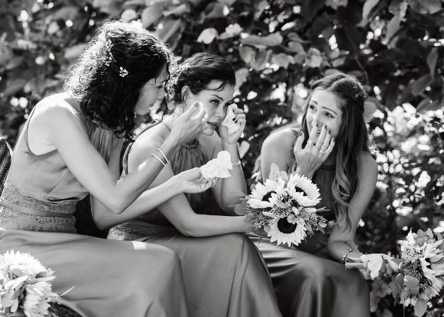 black and white photo of three bridesmaids sat down crying 