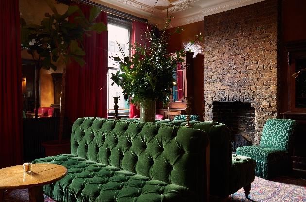 rustic interior of hotel pub brick fireplace velvet green chairs