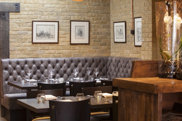 leather brown sofa and wooden tables against brick walls in restaurant 