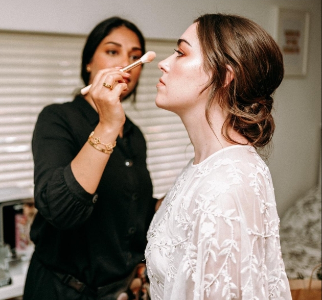 make-up artist applying make up to bride in chair