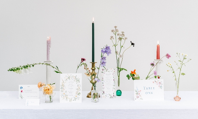 group shot of stationery designs around a display of flowers and candles