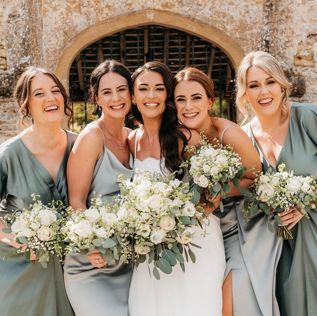 Bridesmaids in green with bride in white holding flowers
