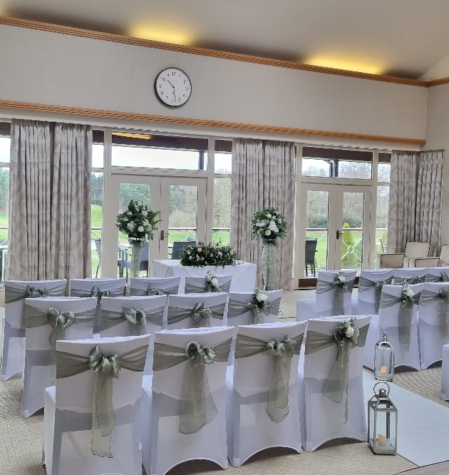 ceremony venue in hotel chairs with white covers and green sashes all looking at windows and view