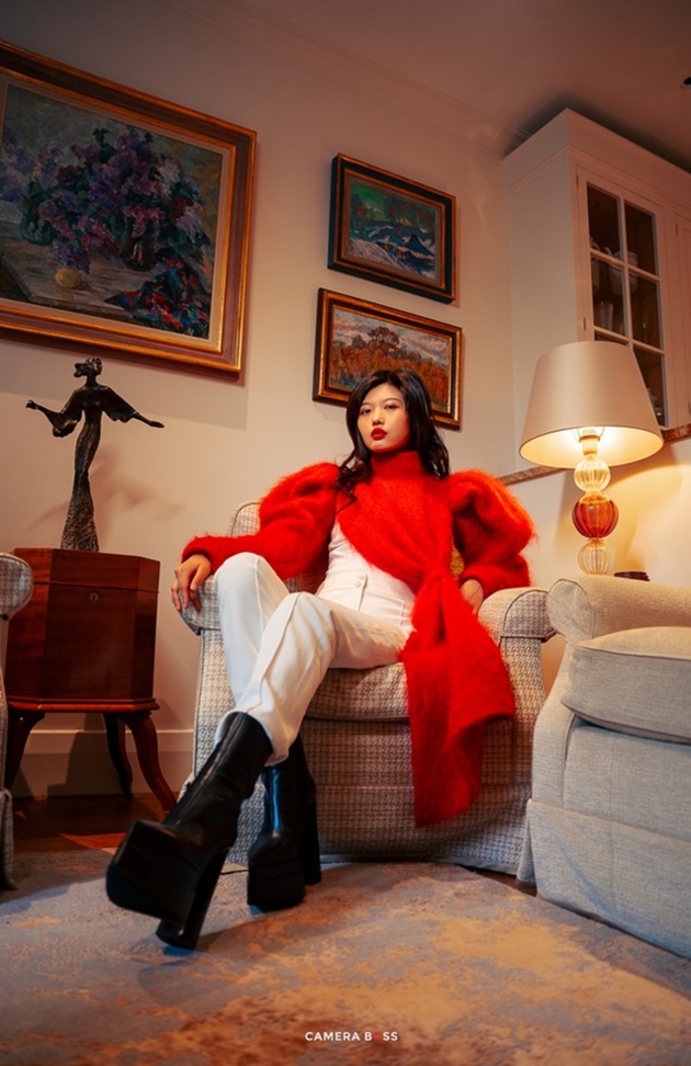 model in white trousers and red coat