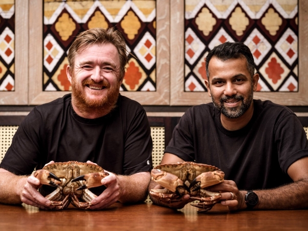Two men holding crabs.