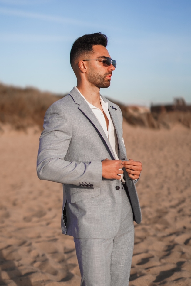 man in light-coloured suit posing on the beach 