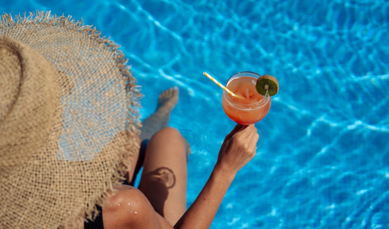 lady sat by the pool holding a cocktail