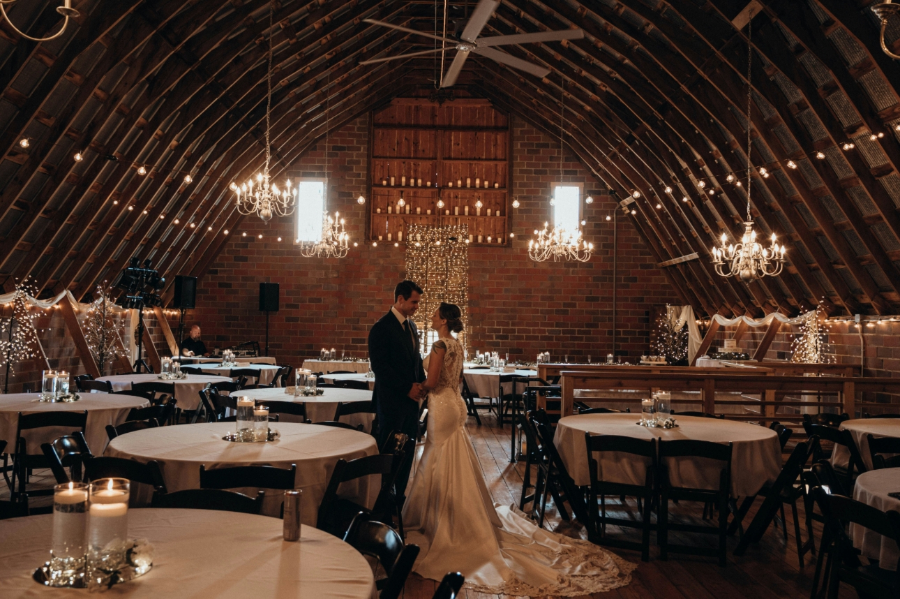 wedding couple in a barn decorated for wedding reception