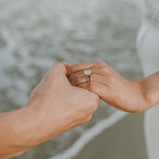 Man holding a woman's hand with an engagement ring on 