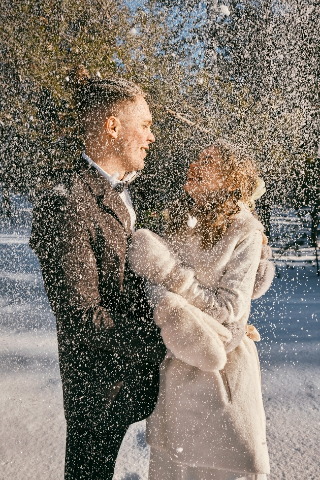 A bride and groom embracing surrounded by snow